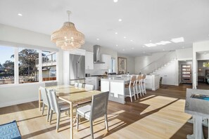 Une cuisine moderne avec des meubles blancs, un îlot central et un lustre suspendu.