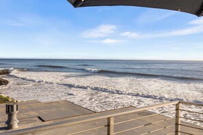 A beach view with a clear sky, waves, and a staircase leading down to the shore.