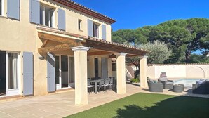 Une maison à deux étages dotée d’un patio aménagé avec des meubles d’extérieur et un barbecue.