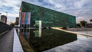 Un edificio moderno con facciata in vetro e una piscina specchiante di fronte.