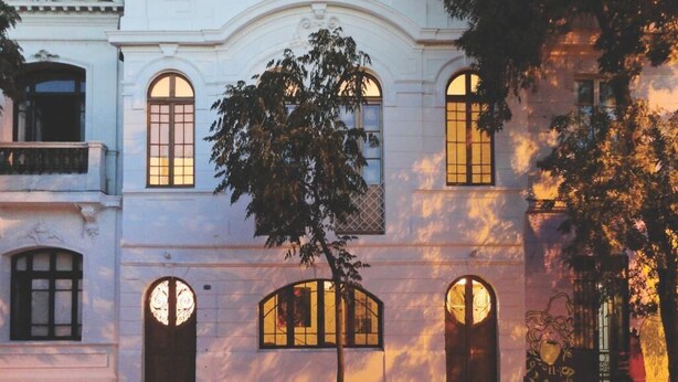 Un edificio con finestre ad arco e un albero di fronte.