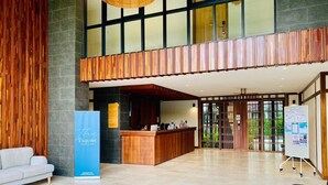 A modern hotel lobby with a reception desk, seating area, and a large information board. - The Title V by The Esquire (Rawai)