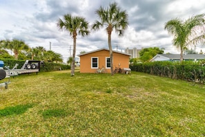 A small house with a lawn, palm trees, and a bicycle. - Cape Key Updated Beach Bungalow (Port Orange)
