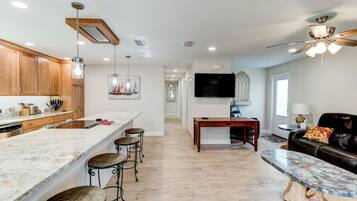 A modern kitchen with a marble island, wooden cabinets, and bar stools.