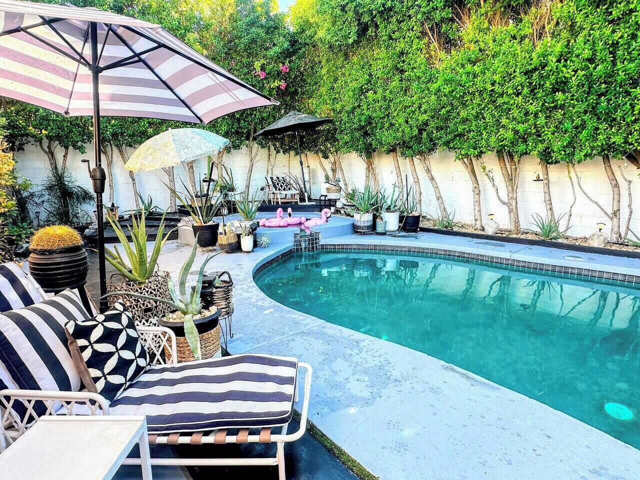 Zona de piscina amb gandules, ombrel·les i plantes en testos.
