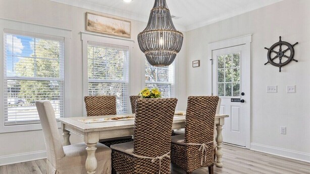 A dining area with a table, chairs, a chandelier, and a door with a sign.