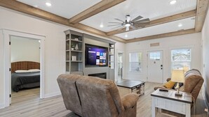 A spacious living room with a large TV, a ceiling fan, and a cozy seating area.