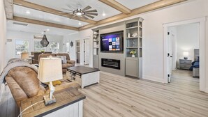 A spacious living room with a fireplace, a television, and a ceiling fan.