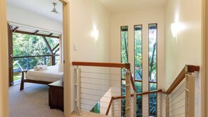 A bedroom with a bed, a wooden headboard, a nightstand, and a window with a view of greenery.