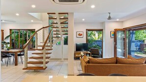 A modern living room with a staircase, a dining area, and a TV.