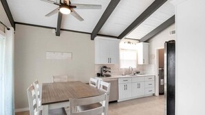 A modern kitchen with white cabinets, a wooden dining table, and a ceiling fan. - Sarasota Coastal Style - Minutes To Siesta Beaches - Casa de Suenos (Sarasota)