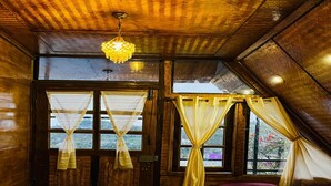 Een gezellig slaapkamer op zolder met een houten plafond, een bed met een paars dekbed en een raam met gele gordijnen.
