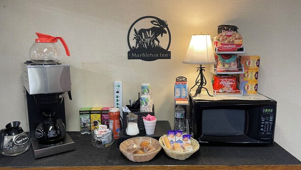 Una kitchenette equipada con cafetera, microondas y diversos alimentos.