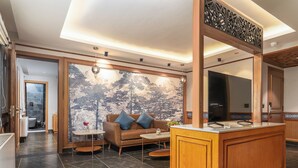 A modern living room with a wooden sofa, a coffee table, and a decorative wall mural. - The Vale Lodge (Anantnag)