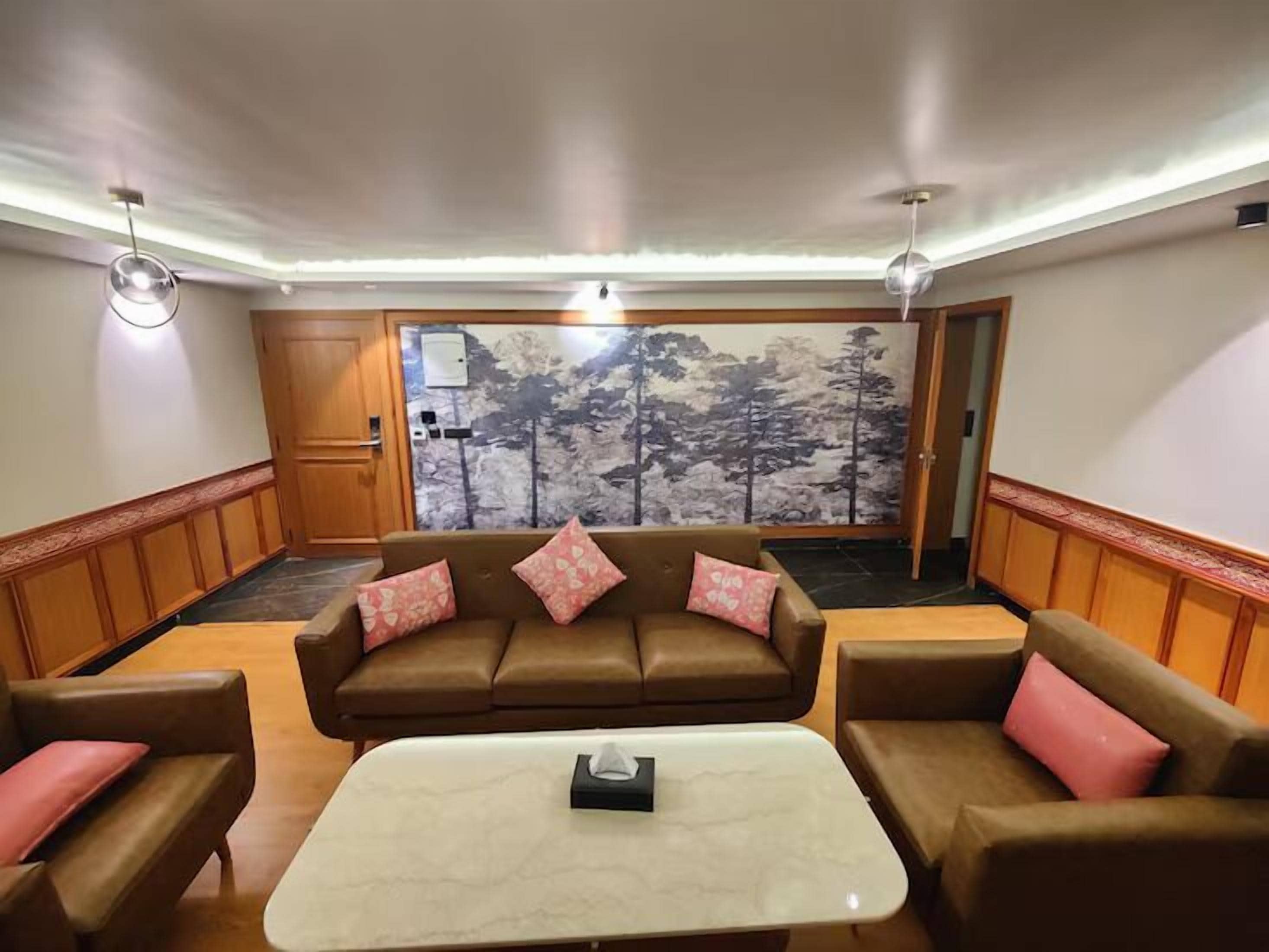 A room with a brown leather sofa set, a white coffee table, and wooden paneling on the walls.