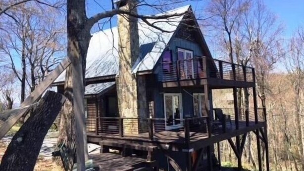 Eine Holzhütte mit einer Holzterrasse, einem Schornstein und einem Balkon.