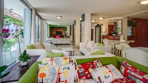 A modern living room with a sofa set, a dining area, and a kitchen visible through an open door. - HOTEL KONRAD (Rimini)
