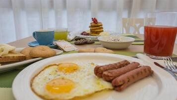 A breakfast setting with eggs, sausages, toast, and a glass of juice on a table.