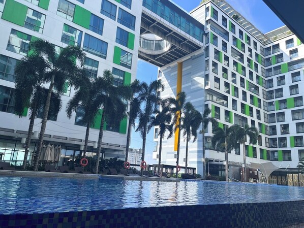 A modern hotel with a pool area, palm trees, and a multi-story building with balconies. - The Wellington-Republic Plaza Airport (Ho Chi Minh City)