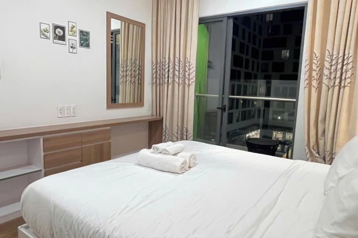 A hotel room with a bed, a mirror, a wardrobe, and a view of a balcony.