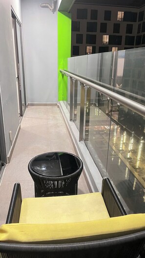 A corridor with a trash bin, a yellow bench, and a glass railing. - The Wellington-Republic Plaza Airport (Ho Chi Minh City)