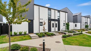 A modern residential building with a symmetrical facade, multiple windows, and a well-maintained lawn.
