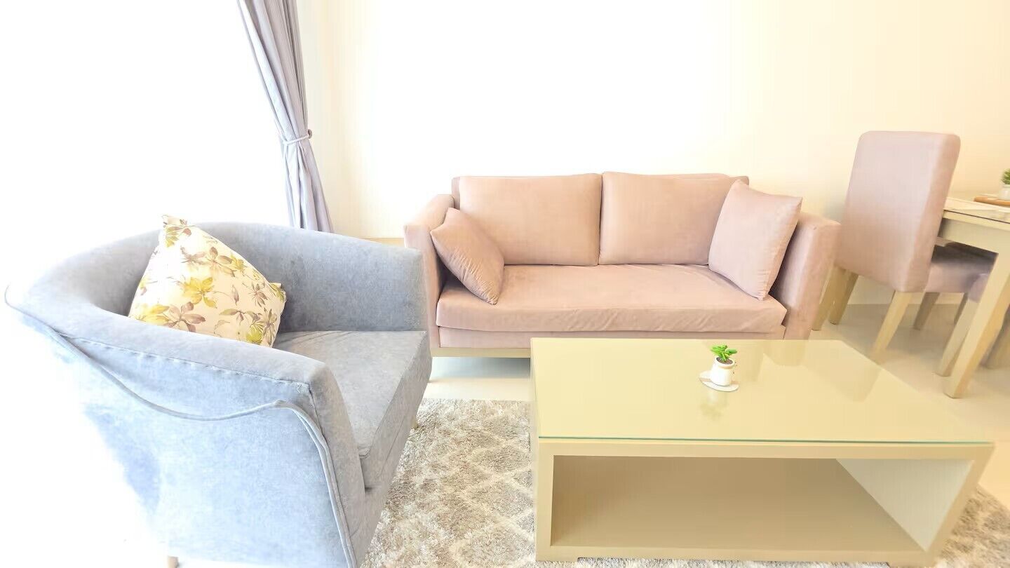 A living room with a sofa, a chair, a small table, and a window with curtains.