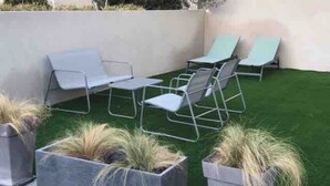 A patio with outdoor seating and planters. - Maison Basalte studio 1 (Agde)