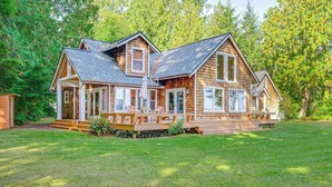 Eine Holzhütte mit Veranda, großen Fenstern und einem grünen Rasen.