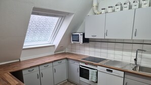 Eine kleine Küche mit Mikrowelle, Backofen und Spüle.