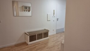 Ein Flur mit einer hölzernen Bank, einer weißen Tür und einem Wandspiegel.