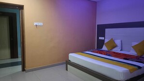 A hotel room with a bed, a door, and a wall socket.