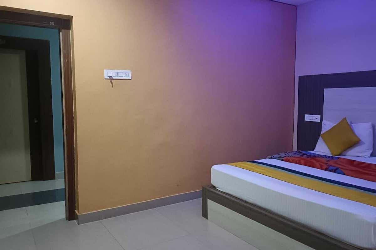 Una habitación de hotel con una cama, una puerta y un enchufe.