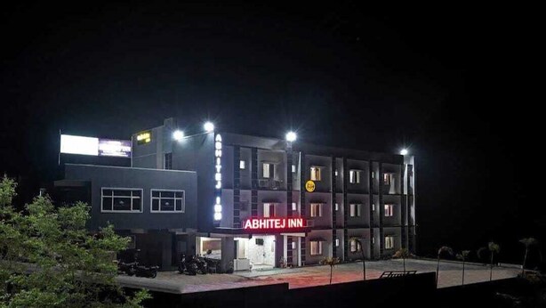 A multi-story building with the sign "ABHITEJ INN" at the ground level, featuring a modern architectural design with multiple windows and a flat roof.