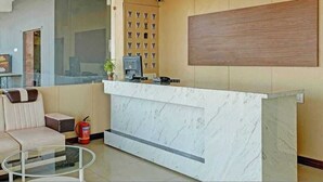 A reception area with a marble counter, a sofa, a coffee table, and a fire extinguisher.