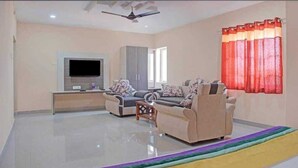 A spacious living room with a flat-screen TV, two sofas, a coffee table, and a ceiling fan.