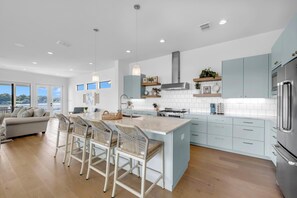 Enjoy cooking in this well-lit kitchen with a central island and bar stools, featuring a refrigerator and light cabinetry.