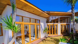Una casa moderna con amplios ventanales, un porche cubierto y un césped cuidado.
