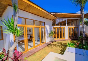 A modern house with large glass doors, a covered patio, and a well-maintained lawn.