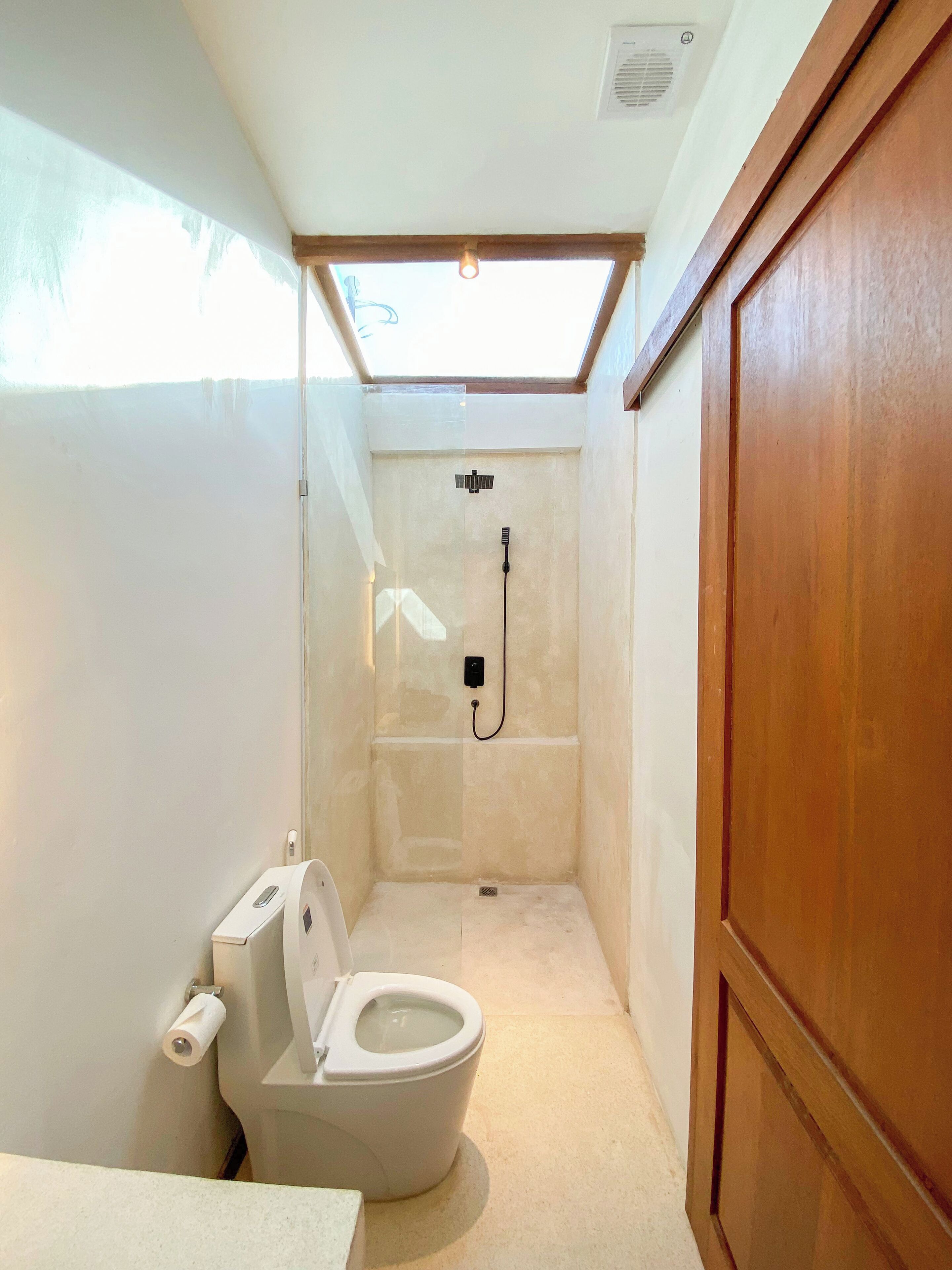 A compact bathroom with a skylight, a shower, and a toilet.