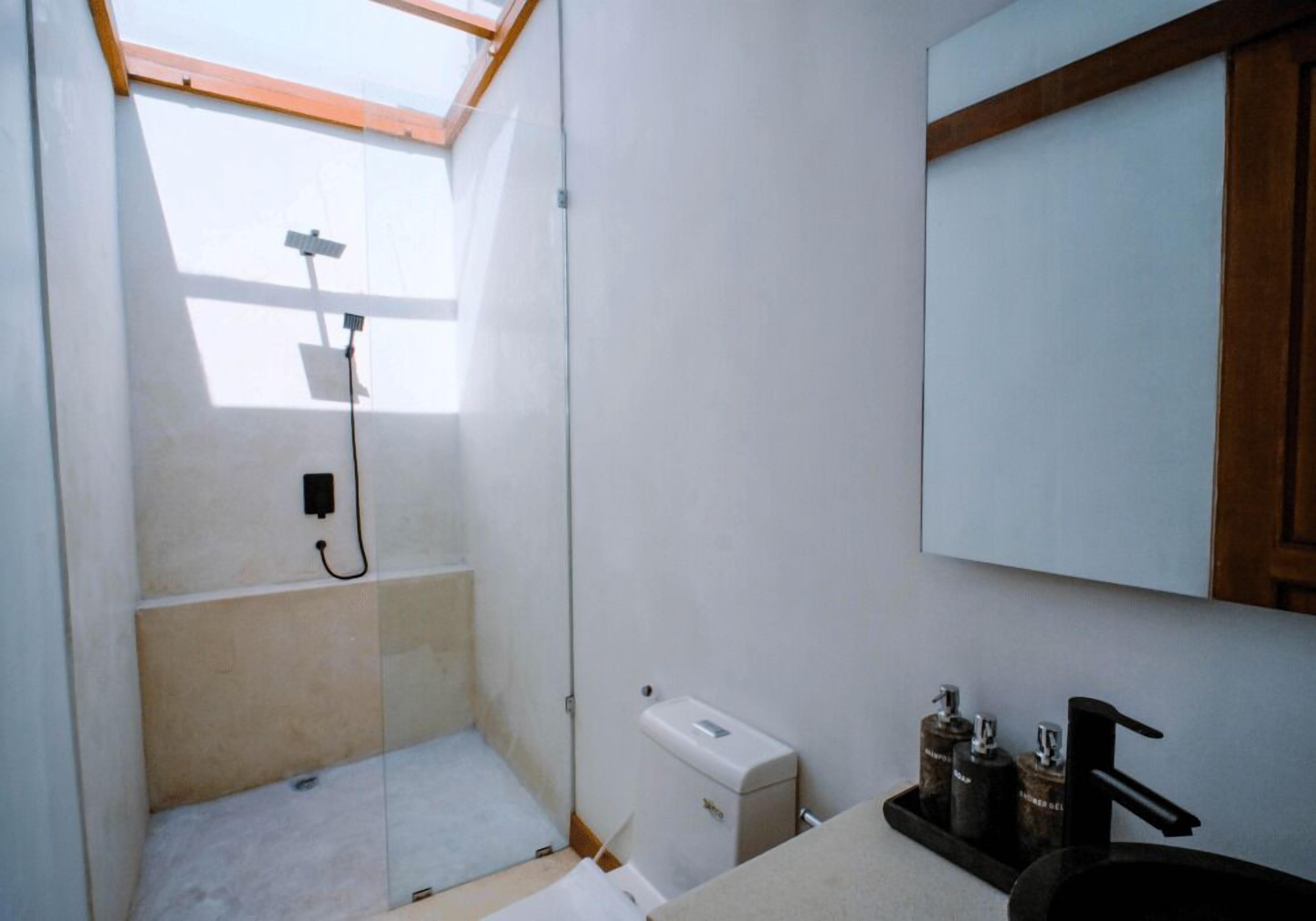 Un baño pequeño y luminoso con tragaluz, lavamanos y retrete.
