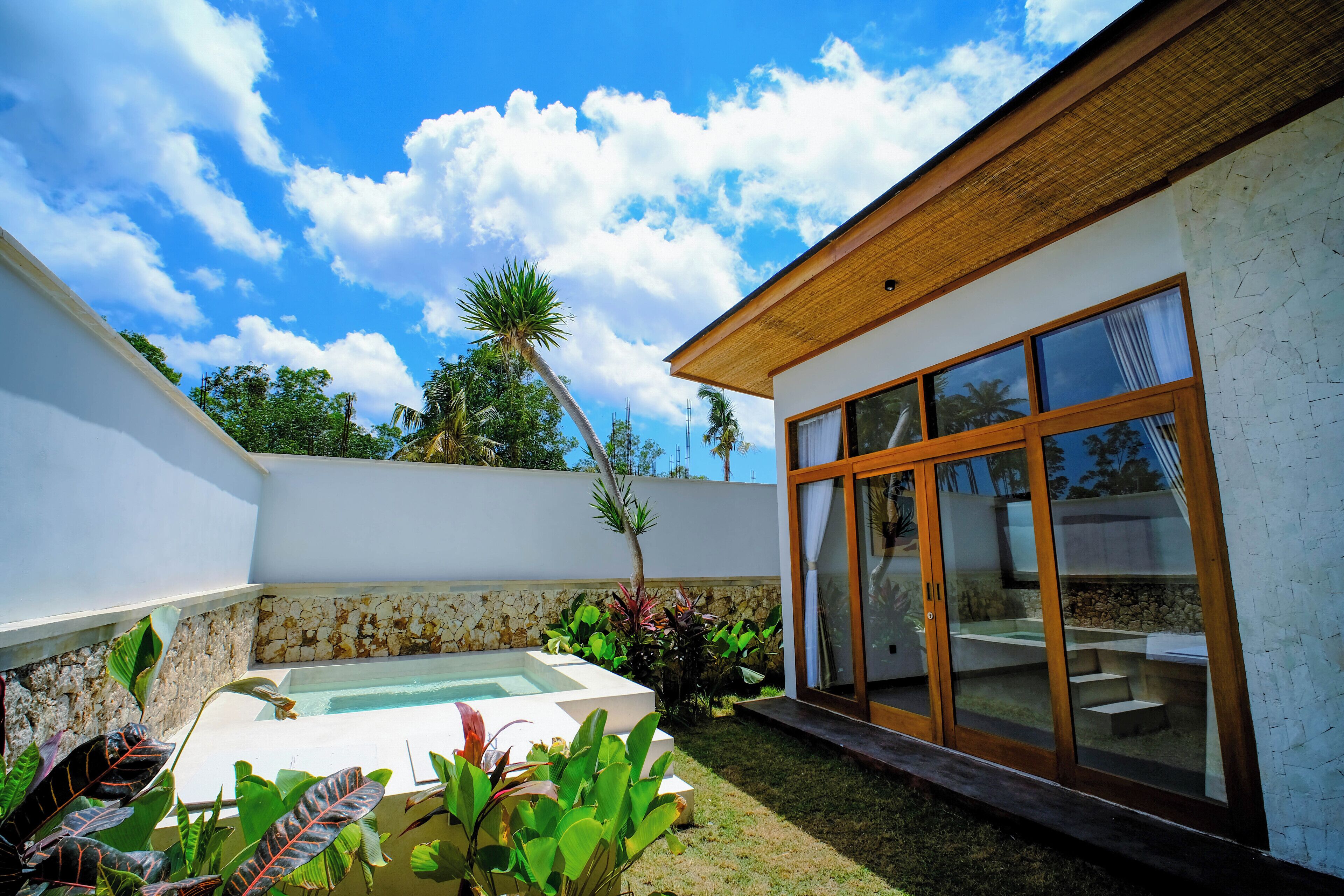 A modern house with a swimming pool, large windows, and a stone wall.