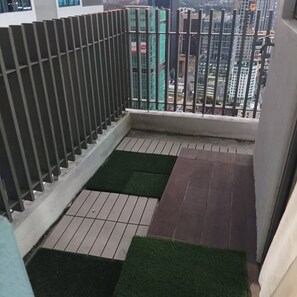 A small balcony with a metal railing, tiled flooring, and a view of city buildings.