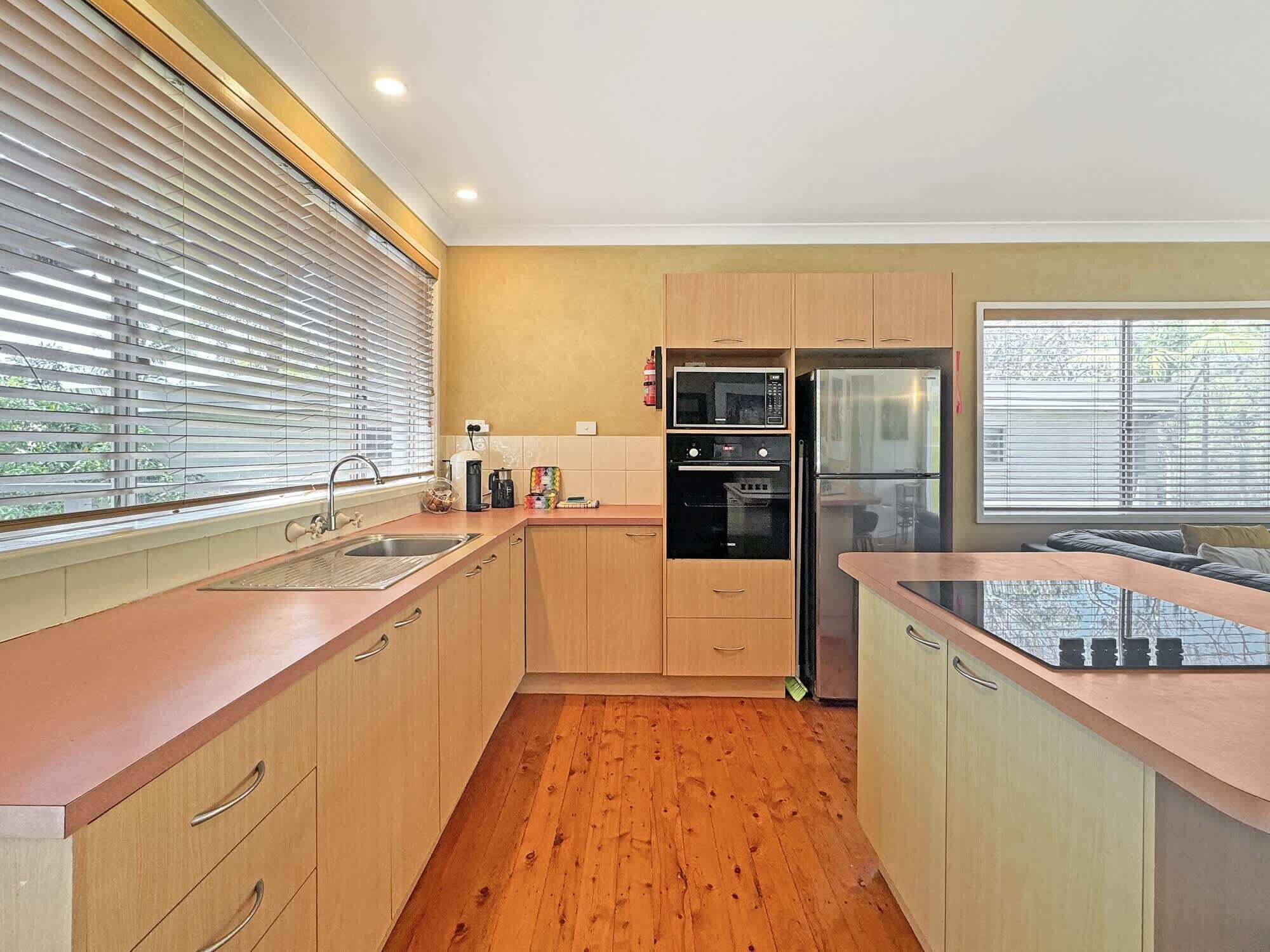 A modern kitchen with wooden cabinets, a stainless steel refrigerator, and a microwave.
