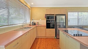 A modern kitchen with wooden cabinets, a stainless steel refrigerator, and a microwave.