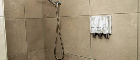 A shower with a handheld showerhead and a wall-mounted faucet.