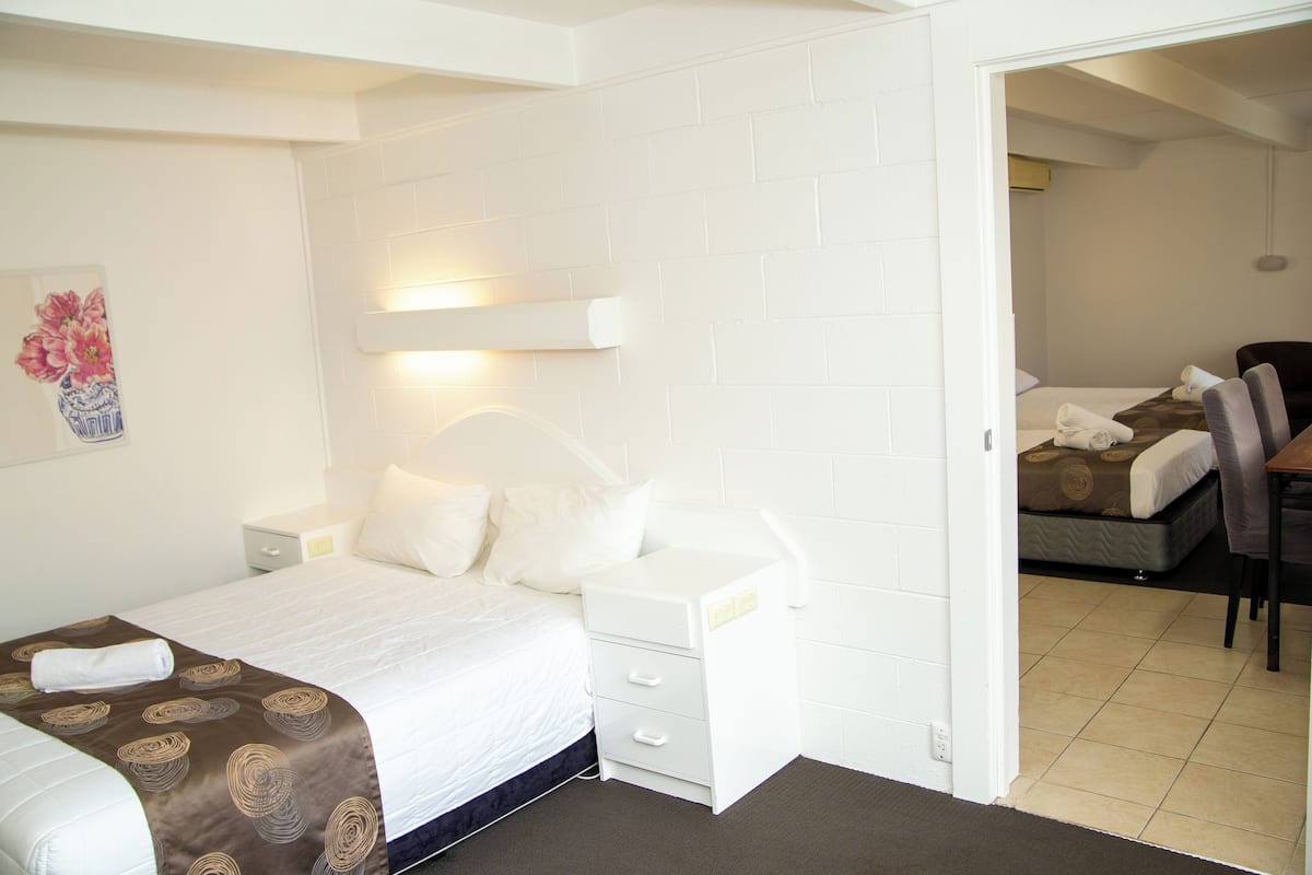 Quarto de hotel com cama, mesas de cabeceira, escrivaninha e uma cadeira.