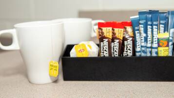 A box of Nespresso coffee pods and two white mugs on a countertop.
