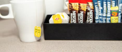 A box of Nespresso coffee pods and two white mugs on a countertop.