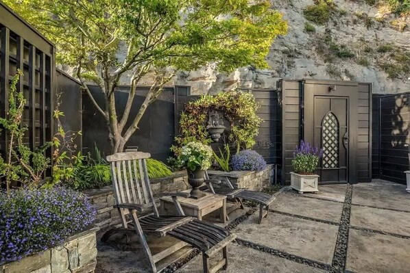 Un patio con un banco de madera, una mesa de piedra y plantas en macetas.